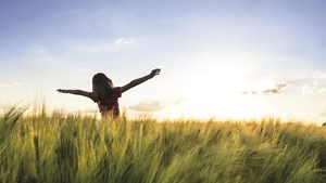 Pige på en mark med armene i vejret