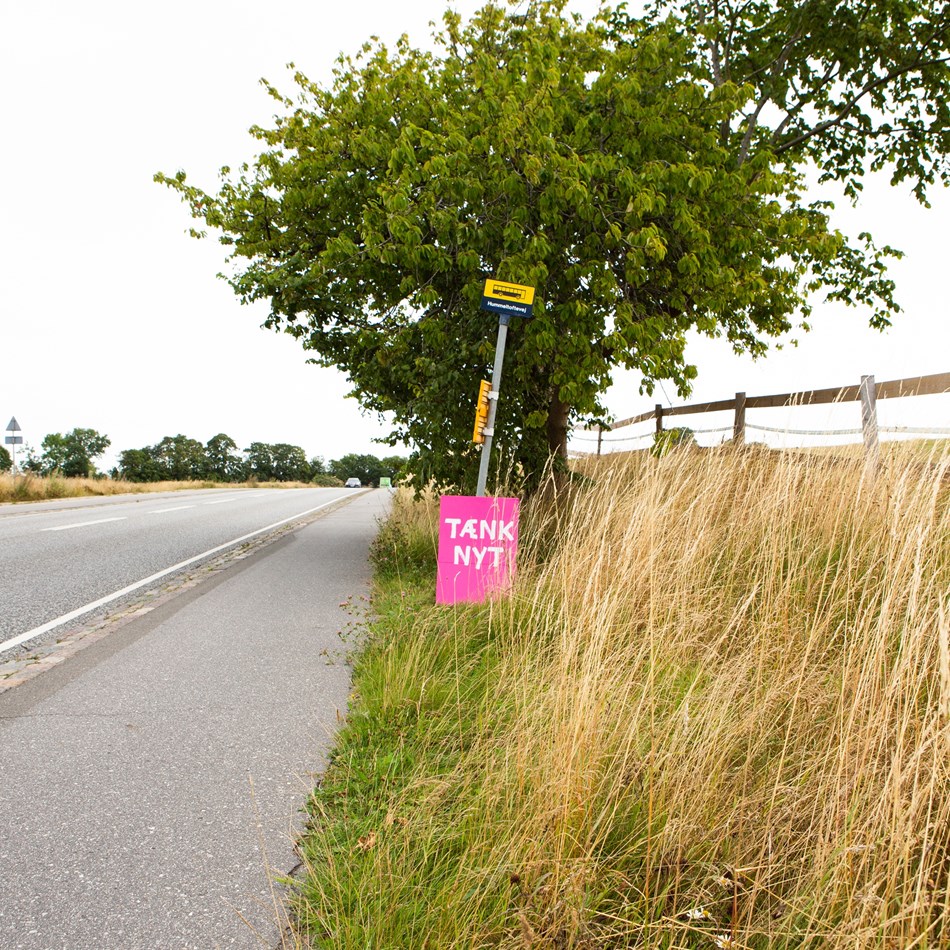 Tænk nyt-skilt ved et øde busstoppested
