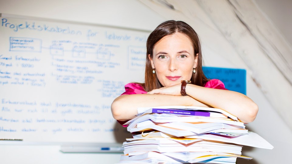 Katrine Robsøe på sit kontor med en stak bøger og rapporter