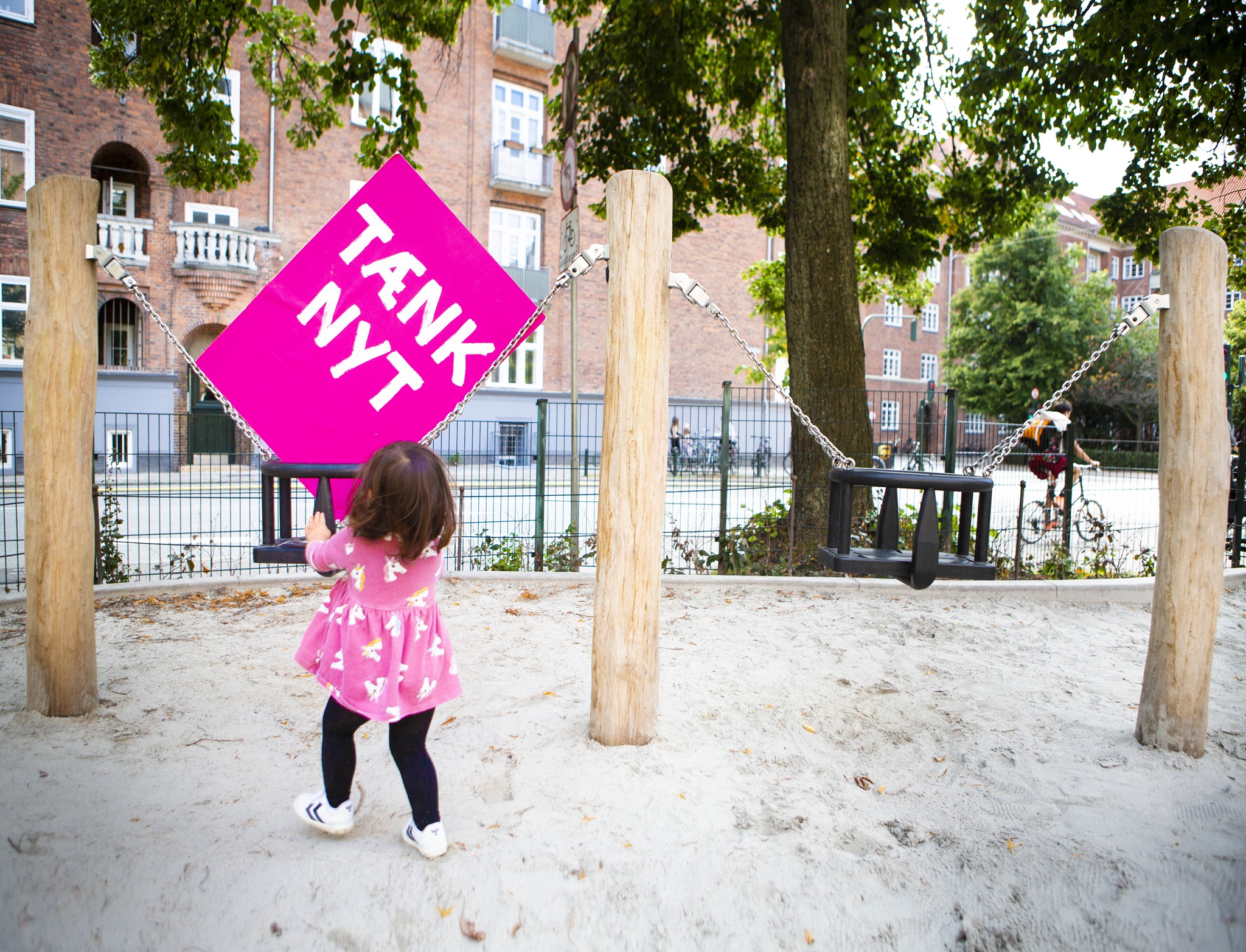 Tænk nyt-skilt bliver gynget af et barn