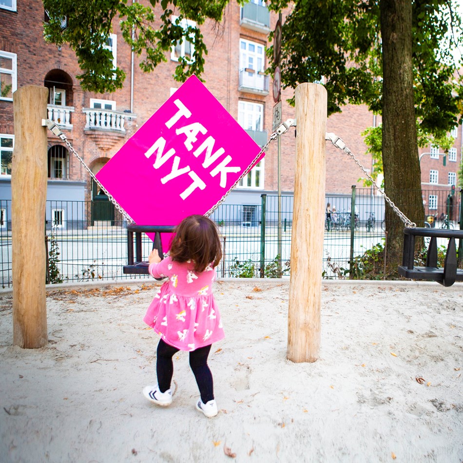Tænk nyt-skilt bliver gynget af et barn