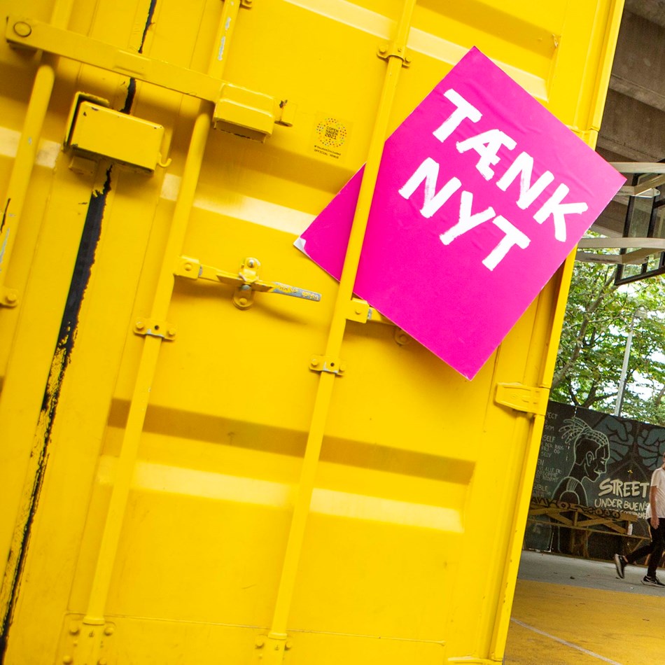 Tænk nyt-skilt foran en gul container